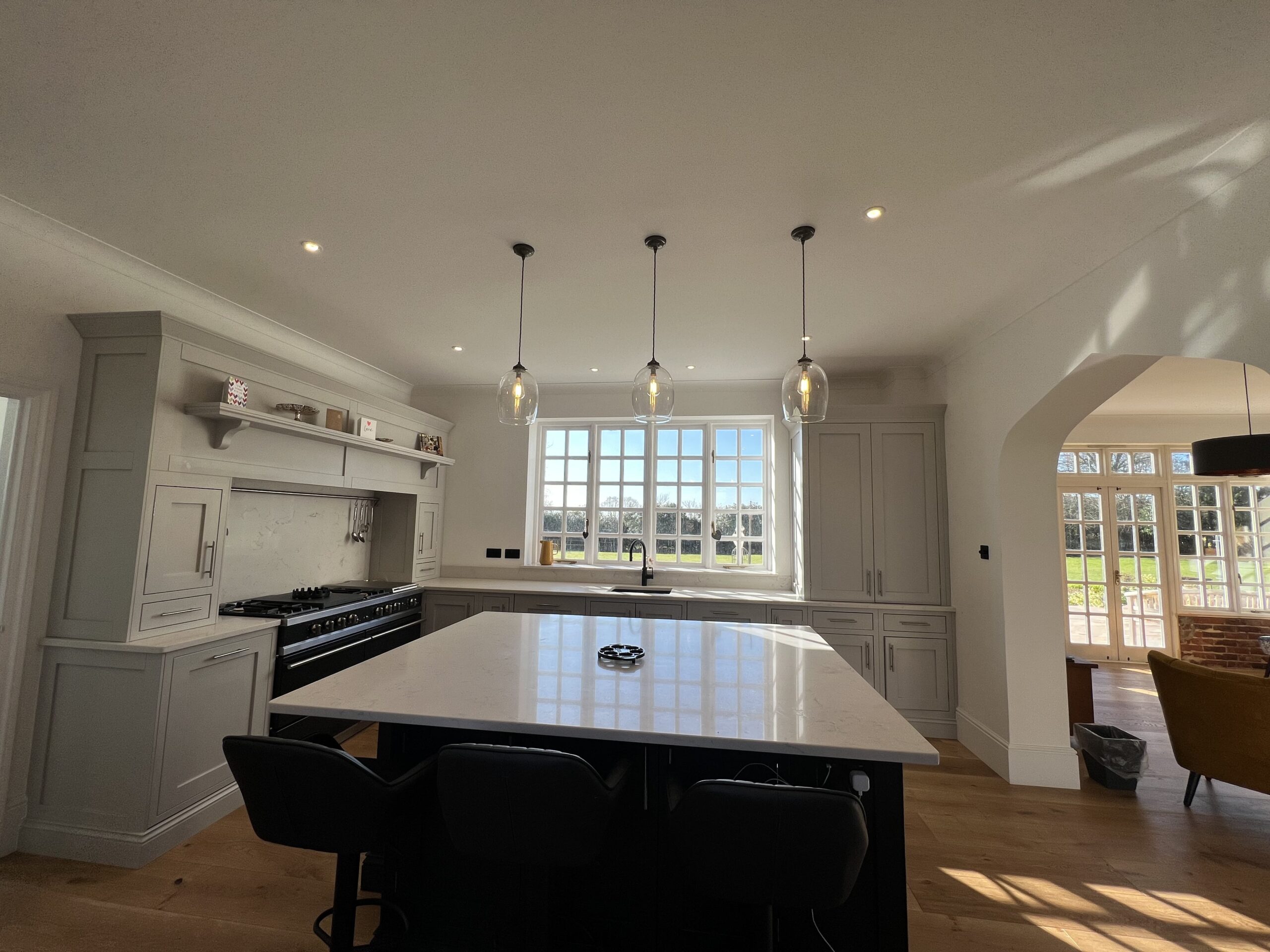 Elegant bespoke kitchen with marble island, pendant lighting, and classic cabinetry, expertly crafted by a professional kitchen designer.