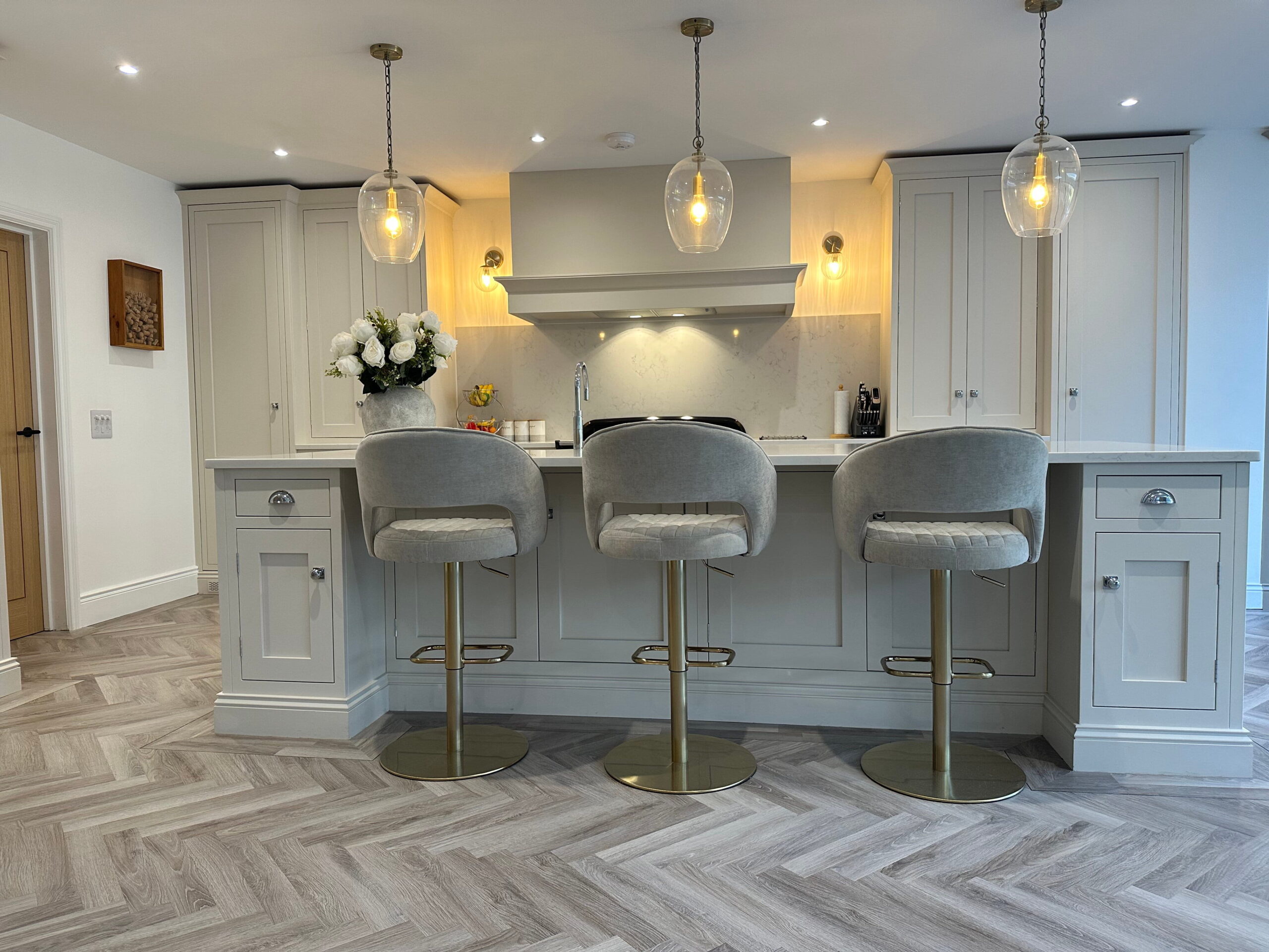 Renovation by a handmade kitchen company in Essex showing three upholstered kitchen stools in grey at worktop
