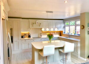 Bespoke luxury kitchens by Regent St James Kitchens showing a kitchen with cream units and white isalnd with white chairs