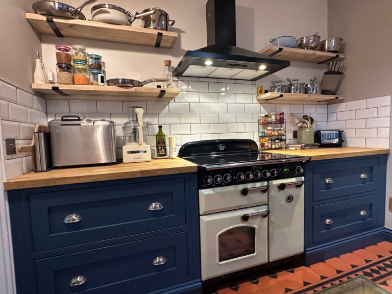 Bespoke kitchen in Gosfield with navy shaker cabinets, Belfast sink, and patterned floor tiles.