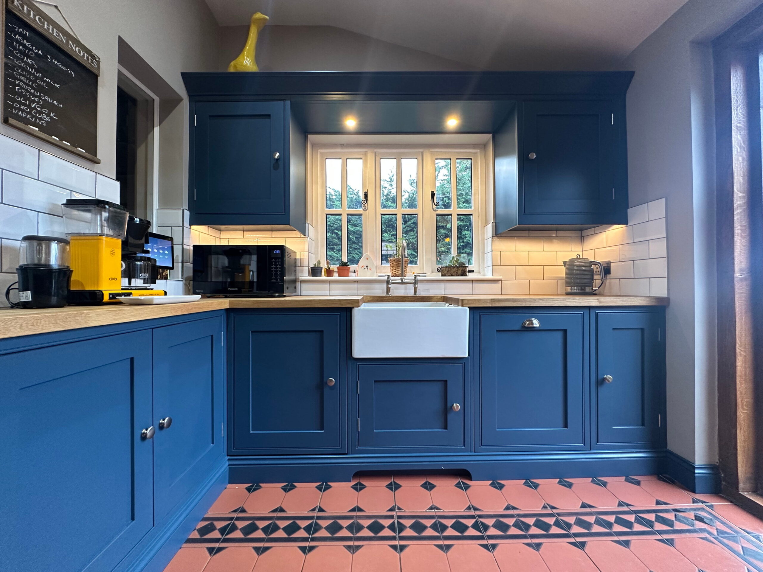 Bespoke kitchens in Gosfield with navy shaker cabinets, oak worktops, and a Belfast sink.