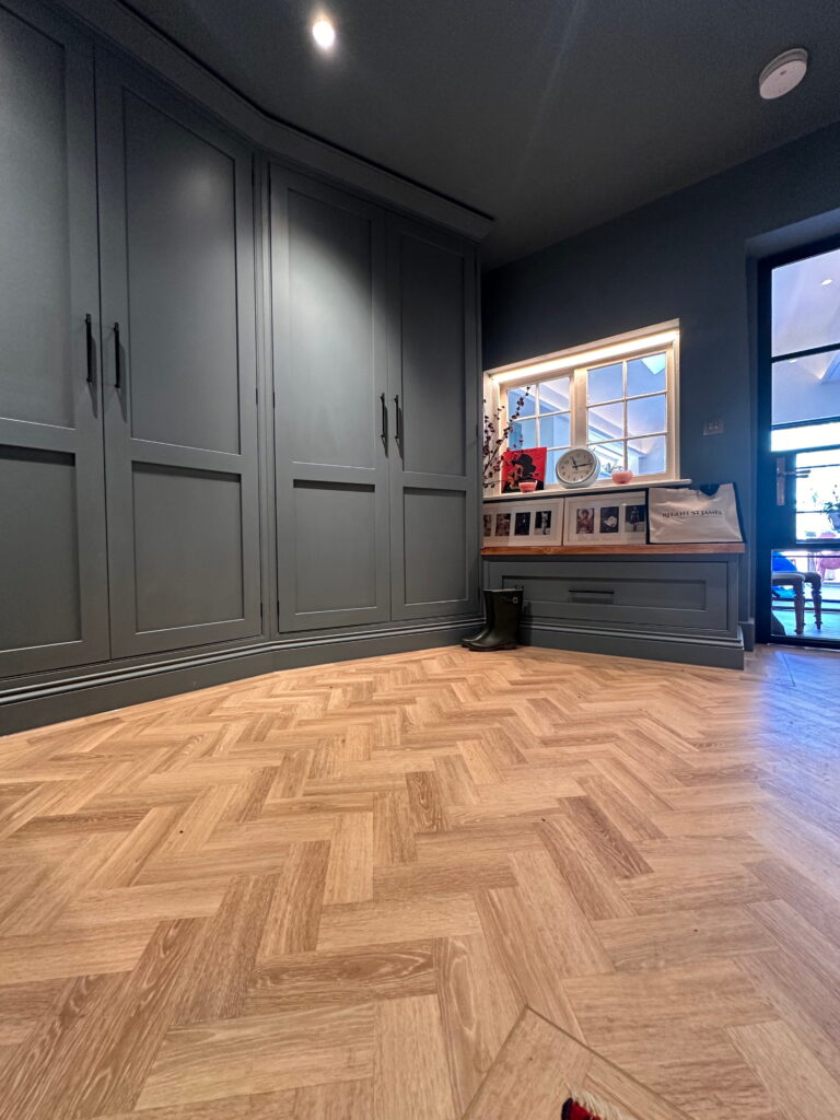 Bespoke Kitchen in Saffron Walden with dark fitted cabinetry and herringbone wood flooring.