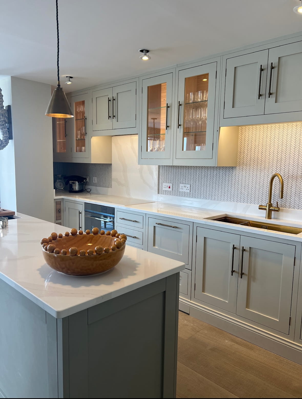 A kitchen with mint green kitchen cabinets, white Essex Granite worktops and Black handles on the cupboard doors.