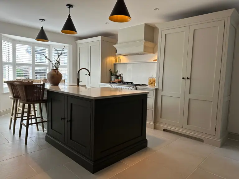 Brown kitchen island with three cone shaped lights above in cream kitchen