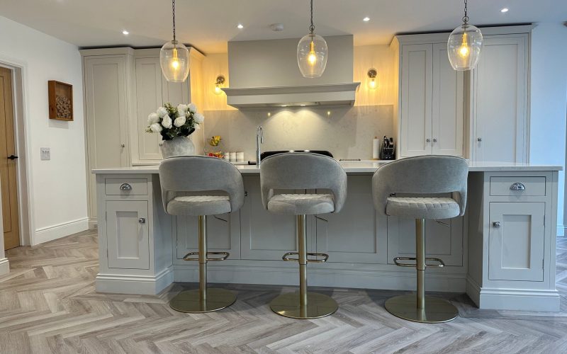 Renovation by a handmade kitchen company in Essex showing three upholstered kitchen stools in grey at worktop