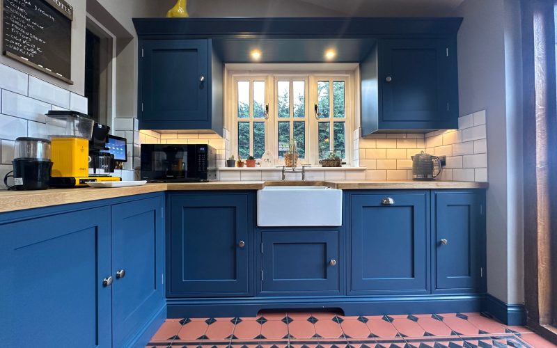 Bespoke kitchens in Gosfield with navy shaker cabinets, oak worktops, and a Belfast sink.