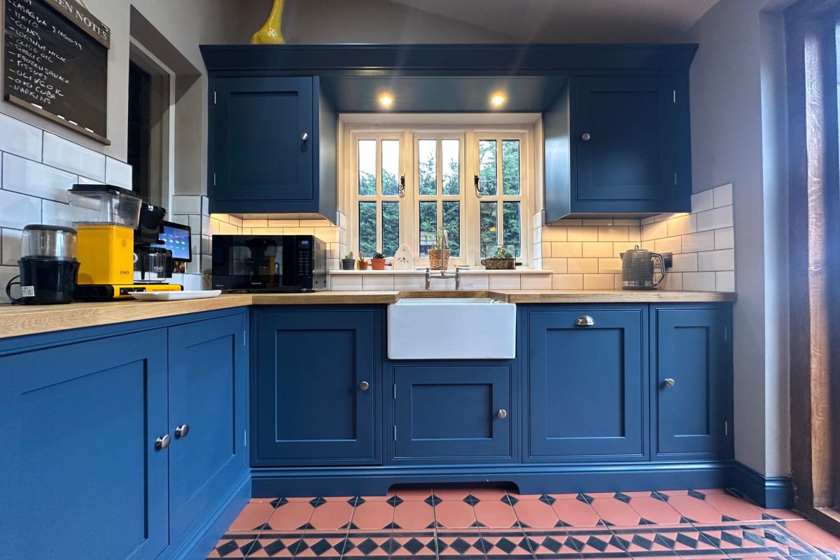 Bespoke kitchens in Gosfield with navy shaker cabinets, oak worktops, and a Belfast sink.